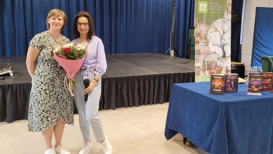 dwie osoby pozują do zdjęcia, jedna trzyma bukiet kwiatów, w tle sala widowiskowa