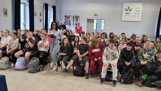 zdjęcie grupowe dzieci, pośrodku stoi autorka, w tle sala widowskowa