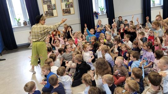 aktor stojący przy grupie dzieci, które podnoszą ręce do góry