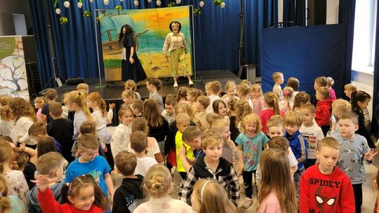 dwóch aktorów na scenie, z przodu sceny stoi grupa dzieci oglądających przedstawienie