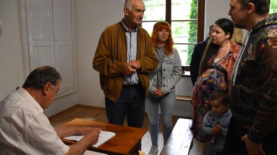 Autor składający autograf na swojej książce, wokół uczestnicy spotkania promującego książkę.