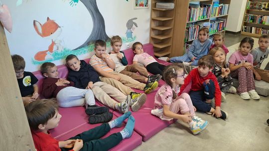 Dzieci siedzą w bibliotece i słuchają fragmentu książki „Kto tam jest? W oceanie”, poznając zwierzęta żyjące w oceanie.